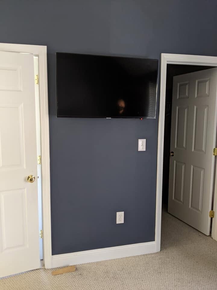 After: the same wall with the television mounted on the bracket and every power and signal cable concealed inside the wall.