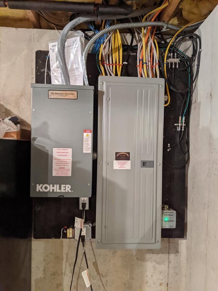 A completed residential load center installed alongside a Kohler automatic transfer switch, with labeled circuits and neatly routed feeders.