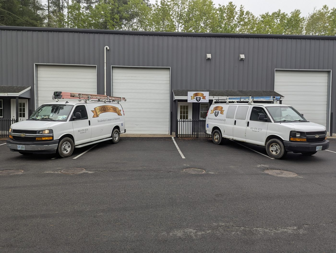Two Daigle Electric service vans parked outside the company's shop bays in Barrington, New Hampshire.