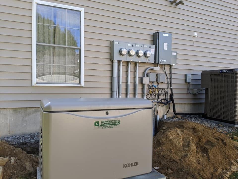 A Kohler standby generator set on a pad beside a home, wired to the meter and disconnects on the exterior wall.
