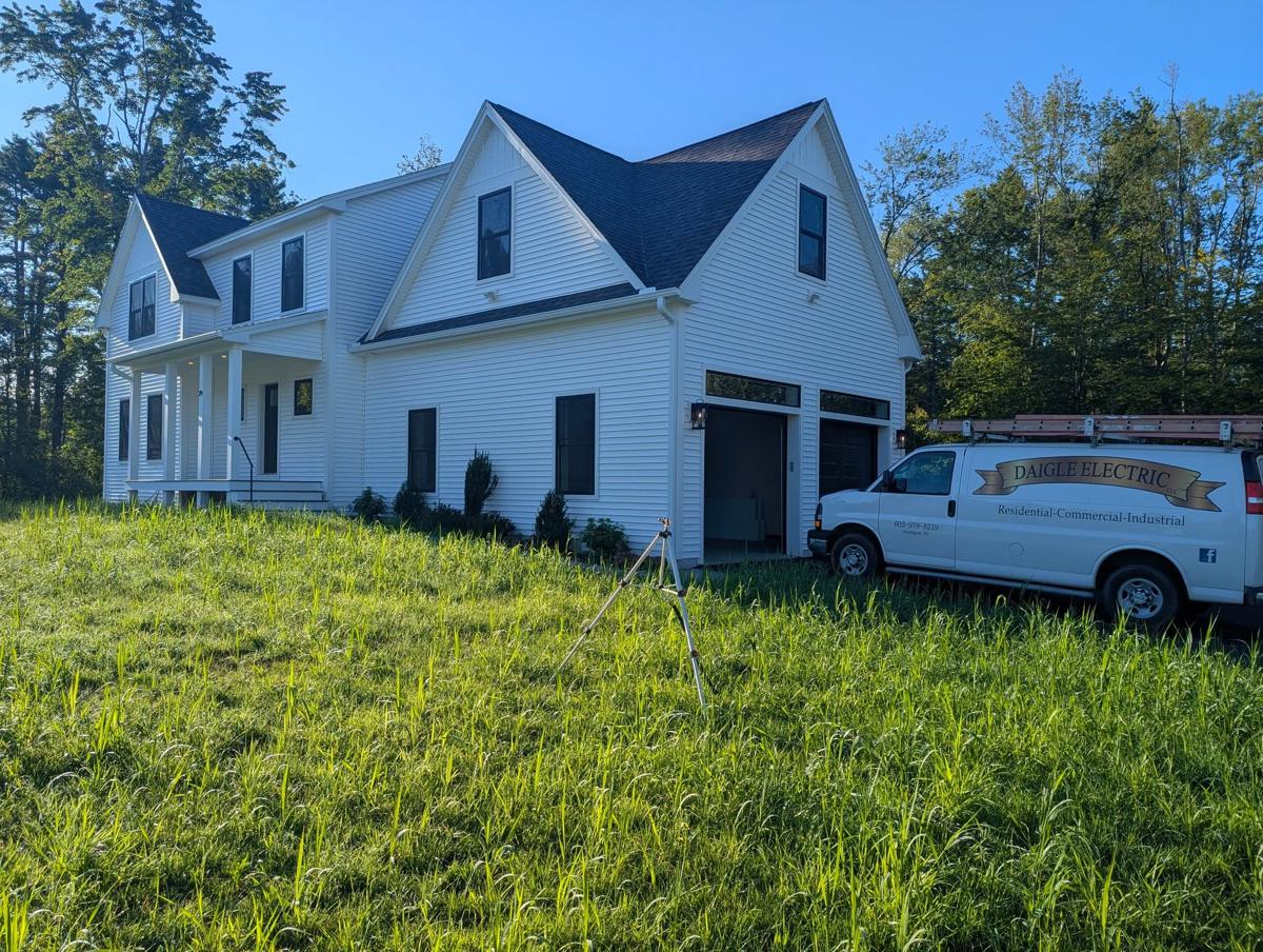 A Daigle Electric service van parked in front of a new home under construction.